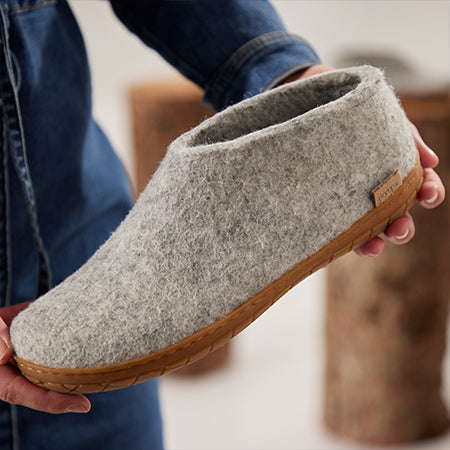 Gray felt slipper with honey natural rubber sole held in hands