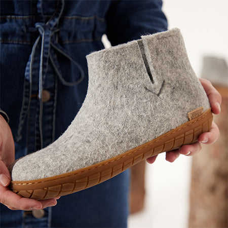 Gray boot with a sole of natural rubber sole held in hands
