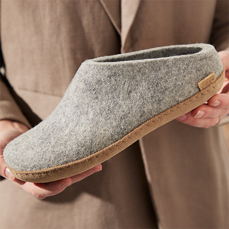 Gray felt slipper with leather sole held in hands